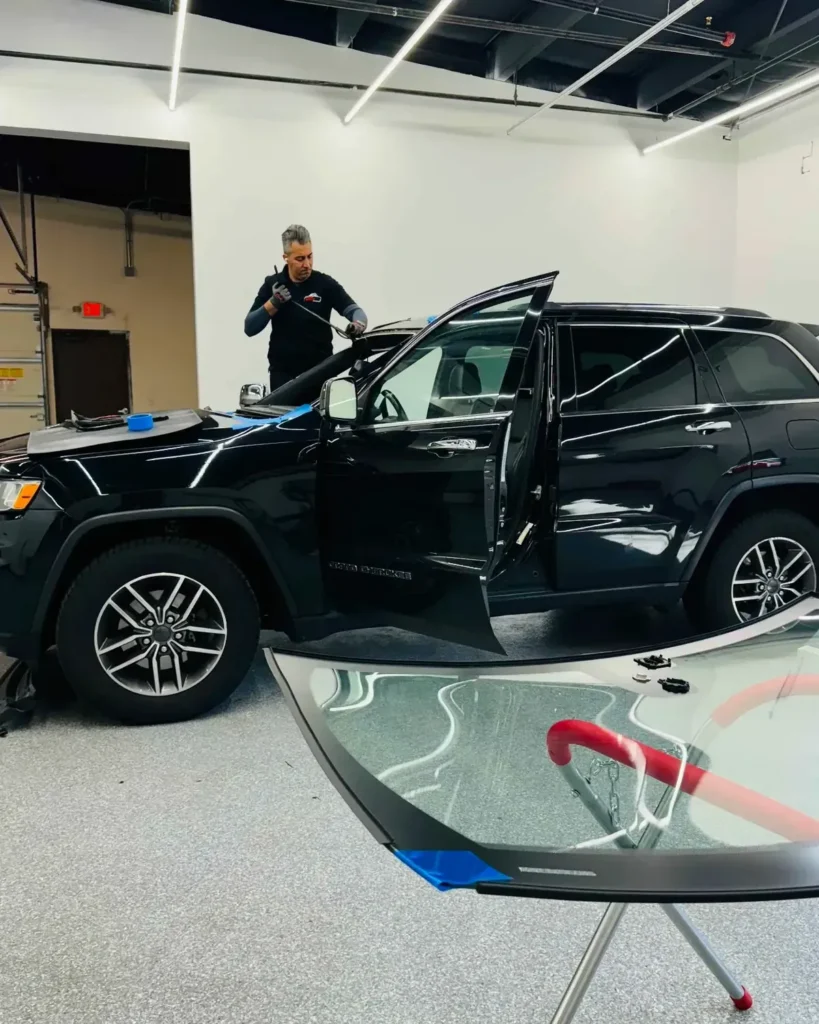 Auto glass technician replacing a windshield on a black SUV